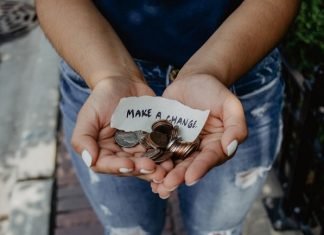 A person holds change and a strip of paper reading "Make a change"